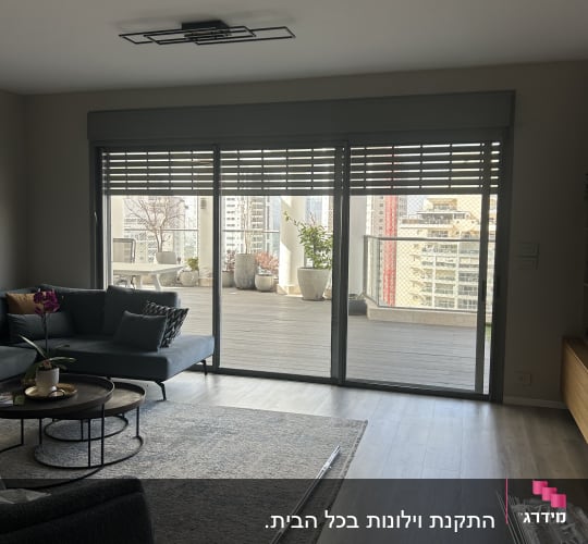 סלון עם חלונות גדולים ותריסים, ספה ושולחן